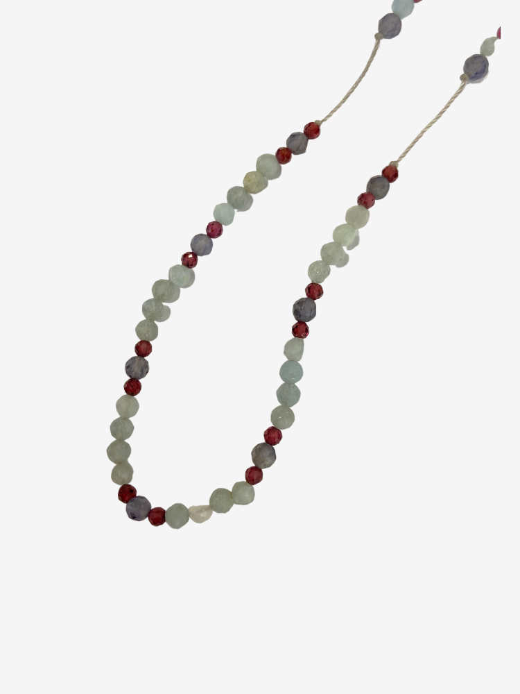 Collier line rakhi me composé de différentes pierres: calcédoine, iolite et zircon violet sur des fils de couleurs gris perle.