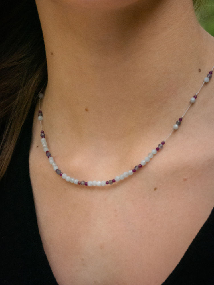 Collier line rakhi me composé de différentes pierres: calcédoine, iolite et zircon violet sur des fils de couleurs gris perle.
